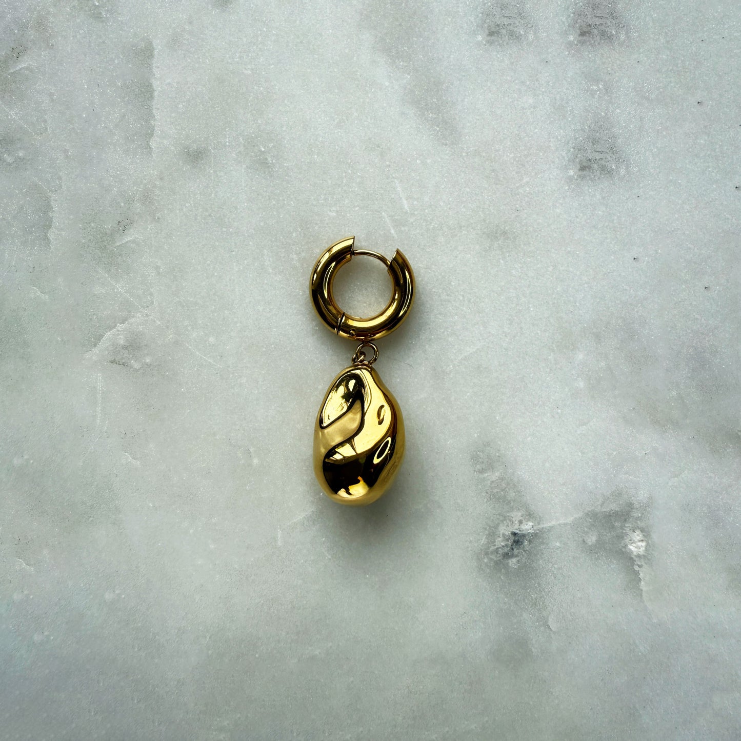 A Single Earring With A Gold Pearl Pendant